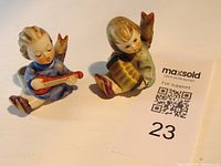 Two Goebel figurine candleholders shown together with auction tag for scale. Child musicians with candleholders visible.