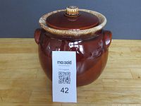 Front view of the vintage brown Hull Pottery bean pot with lid and textured lighter rim.