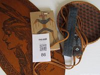 Items arranged on carved wooden plaque showing Indigenous woman and smaller wooden figure, basket and headband.