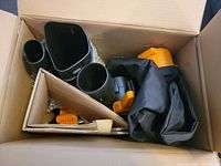 Top view of the open box showing the black and orange Worx leaf blower vacuum components including blower nozzles and vacuum bag.