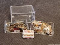 Overall view of the two clear acrylic drawers filled with mixed costume jewelry and the decorative porcelain box placed in front.