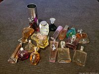 Full view of 15 assorted perfume bottles arranged on grey fabric, various shapes and colors