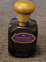 Front view of the nearly full perfume bottle with gold rounded cap and clear label seen on a carpeted surface.