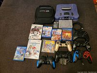 Wide view showing Nintendo 64 console, PlayStation One console, carrying case, controllers and game cases laid out