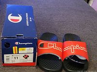 Pair of vintage Champion slide sandals next to original box, size label visible showing US 11.
