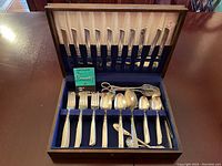Flatware set in wooden case with knives in lid section and forks, spoons in bottom section