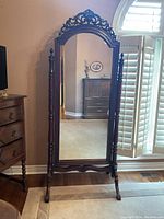 Full view of antique-style full length dressing mirror with carved wood frame and stand.