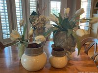 Photo showing two beige ceramic vases with brown rims and artificial white tulip floral arrangements plus the tall ceramic pitcher with dried hydrangeas and antler-like decorations