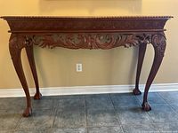 Front view of the carved wooden hall table showing ornate apron and legs.