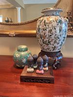 Photo showing the large lotus flower urn on a wooden stand, the green ginger jar, and Buddha figurines on a wooden base.
