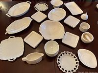 Full layout of all white ceramic dinnerware and serveware pieces on table.