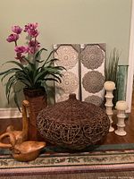 Full view of the lot showing basket, plant, wooden bird figure, candlesticks, vase, and wall art panels