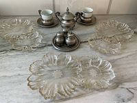 Photo showing arrangement of all items on countertop: metal cups with saucers, glass serving dishes, covered dish, tray with spice containers
