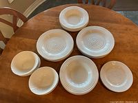 Top view of the plates and bowls arranged on a wooden table, showing various sizes and textured concentric circle design