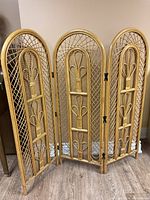 Full view of four-panel wicker room divider showing woven lattice and decorative loops on each panel