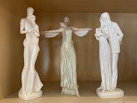 Three Royal Doulton porcelain figurines displayed in a wooden shelf, showing their full forms and details.