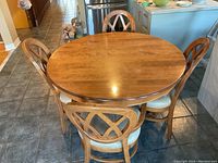 Round wooden dining table with four matching chairs, showing the table top and chair backs.