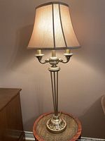 Full view of vintage brass table lamp with fabric beige shade, lit to show lighting intensity and overall look.