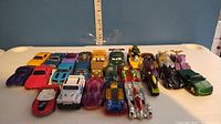 Photo of 22 assorted toy cars laid out on a table with a ruler in the background for scale
