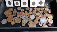 Photo showing a large assortment of different commemorative coins and tokens spread out on a black surface, some in holders with dates and details visible