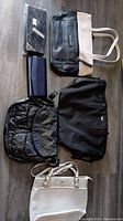 Overview of six bags including black and beige tote, black textured shoulder bag, white Ann Klein bag, and three clutches/wallets