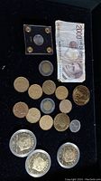 Overview photo showing the collection of coins and a 2000 Lire banknote arranged on black surface.