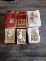 Full lot of six Lenox collectible ornaments and figurines, some in original red display boxes with gold tassels, others wrapped in white foam within boxes.