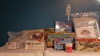 Photo showing the collection of model kits and books including the Blohm & Voss BV 141 model kit, various books in plastic bags, and a container of craft glitter
