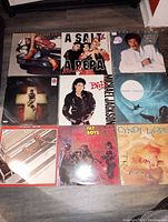 Top-down photo showing all nine vinyl album covers arranged in a 3x3 grid on the floor.