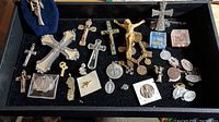 Full overview of religious lot showing crosses, crucifixes, medals, and pins arranged on black velvet tray.