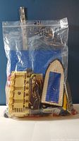 Front view of the sealed plastic bag showing large LEGO pieces including a blue baseplate and yellow and cream colored bricks, the bag is marked '2 lb'.