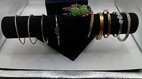 Bracelets arranged on black display stand showing various metal finishes and designs including flexible and rigid bangles.