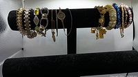 Bracelet display on black velvet horizontal bars showing a variety of bracelets, metal and stretch, side view revealing charm and decorative details