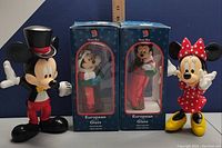 Mickey and Minnie Mouse poseable plastic figurines and two boxed European style glass Christmas ornaments featuring Mickey and Minnie Mouse.