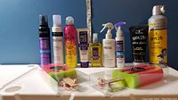 Full view of all 12 items including hair care sprays, mousses, creams, serums, and two popsicle-shaped shower sponges