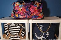Wide shot showing Vera Bradley floral duffle on top, striped beach bag bottom left, and denim anchor beach bag bottom right