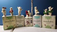 Five sets of Snowbabies figurines displayed on their respective boxes against a blue background, showing all pieces included in the lot.