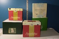 Photo of original boxes for Snowbabies collection including red, green, and blue boxes with branding