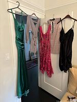 Full view of all five dresses hanging on a white door showing colors and styles