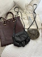 Four handbags displayed on a light fabric surface showing size and style variety.