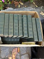 Box of green hardcover vintage books with gold embossed titles, mainly Mark Twain volumes.