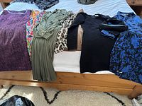 All eight dresses and two handbags displayed on a bed showing various colors and styles