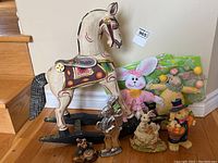 Overall view of wooden rocking horse with removable head and grouping of Easter and animal-themed figurines including rabbits and bears.