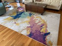 Full view of the rug laid out in living room showing overall abstract pattern and size.