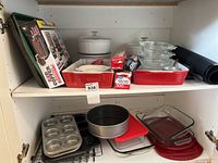 Full cabinet view with baking dishes, pans and glass casserole dishes stacked