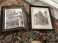 Both prints framed and placed on a patterned carpet, showing entire prints and frames.