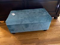 Closed view of teal velveteen tufted blanket box showing top and overall shape