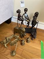 Overall assortment of brass and metal decor items including figurines, angels, elephant, wall hook and candle holder.