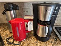 Overview of all items on counter: Toastmaster electric kettle (red), Melitta coffee maker with stainless steel thermal carafe, Toastess coffee grinder box, stainless steel airpot carafe.