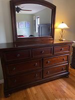 Full front view of dark brown wood dresser with attached arched mirror